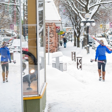 Woman walking downtown Nelson BC carrying cross country skis