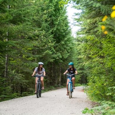 Two women cycling on the Great Northern Rail Trail above Nelson, BC on an ebikes