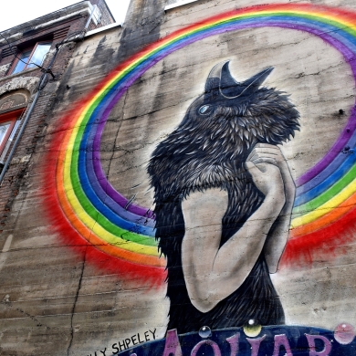 A mural  of a black bird head on a human's body from the Nelson BC Mural Festival