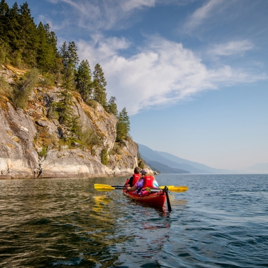 Two people on a double kayak paddling on Kootenay Lake near Kaslo, BC