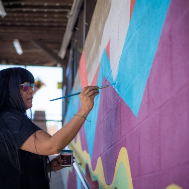 An artist painting a colourful mural at Ainsworth Hot Springs Resort