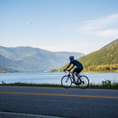 A road cyclist pedalling along the shores of Kootenay Lake.