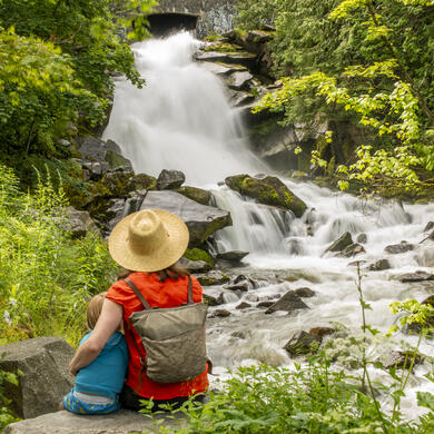 A mother and son sitting in front of Cottonwood Falls in Nelson BC.