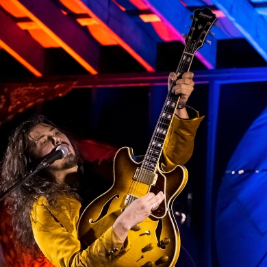 Guitarist playing music in an indoor venue.