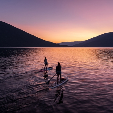 Two paddle boarders on Kootenay Lake paddling into the sunset