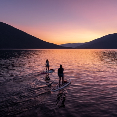 Two paddle boarders on Kootenay Lake paddling into the sunset