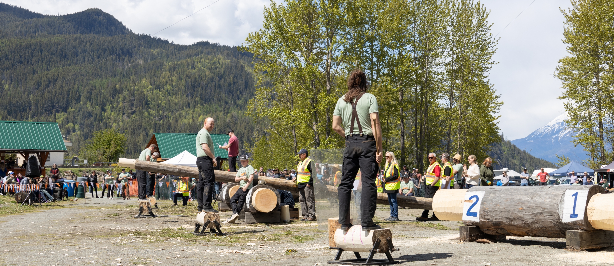 People standing on logs with axes preparing to participate in the Kaslo Logger Sports