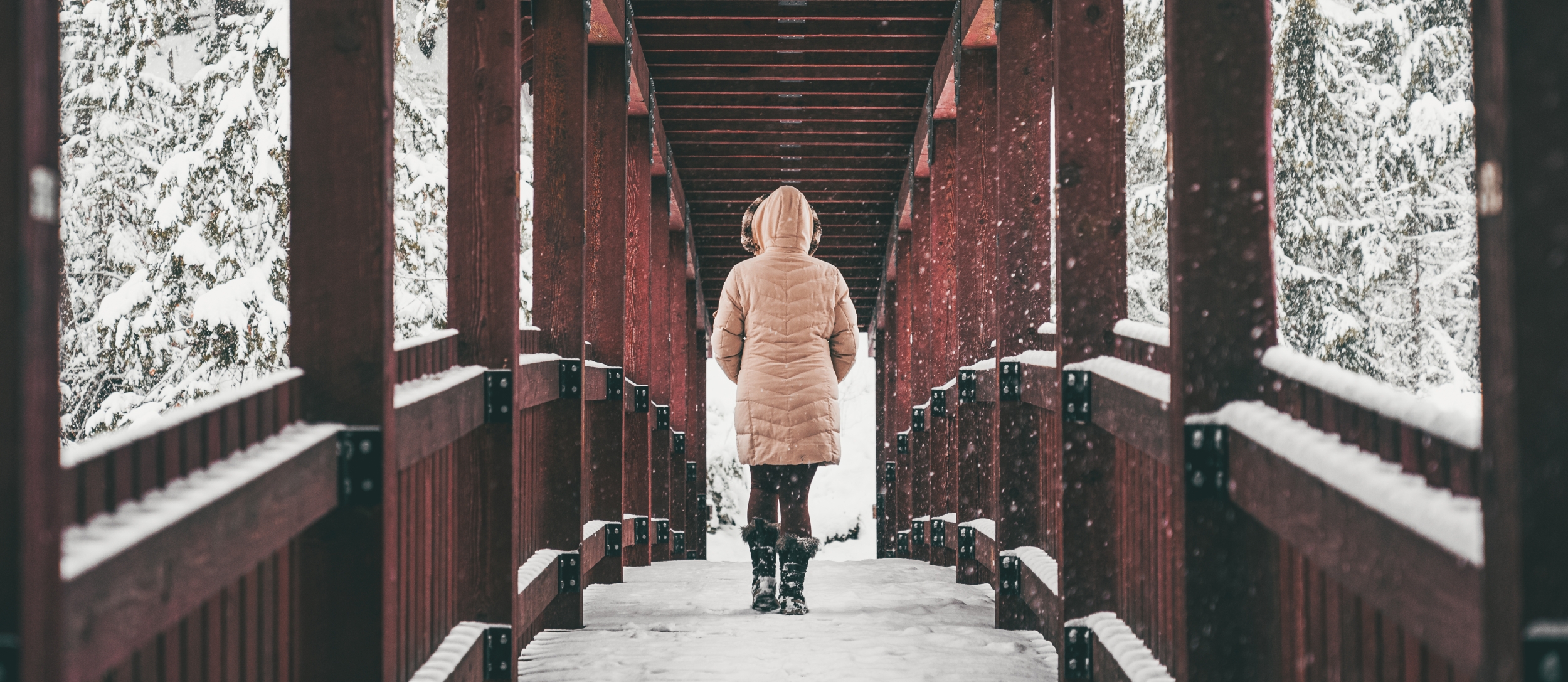 Person walking across one of the red bridges on the Kaslo River Trail