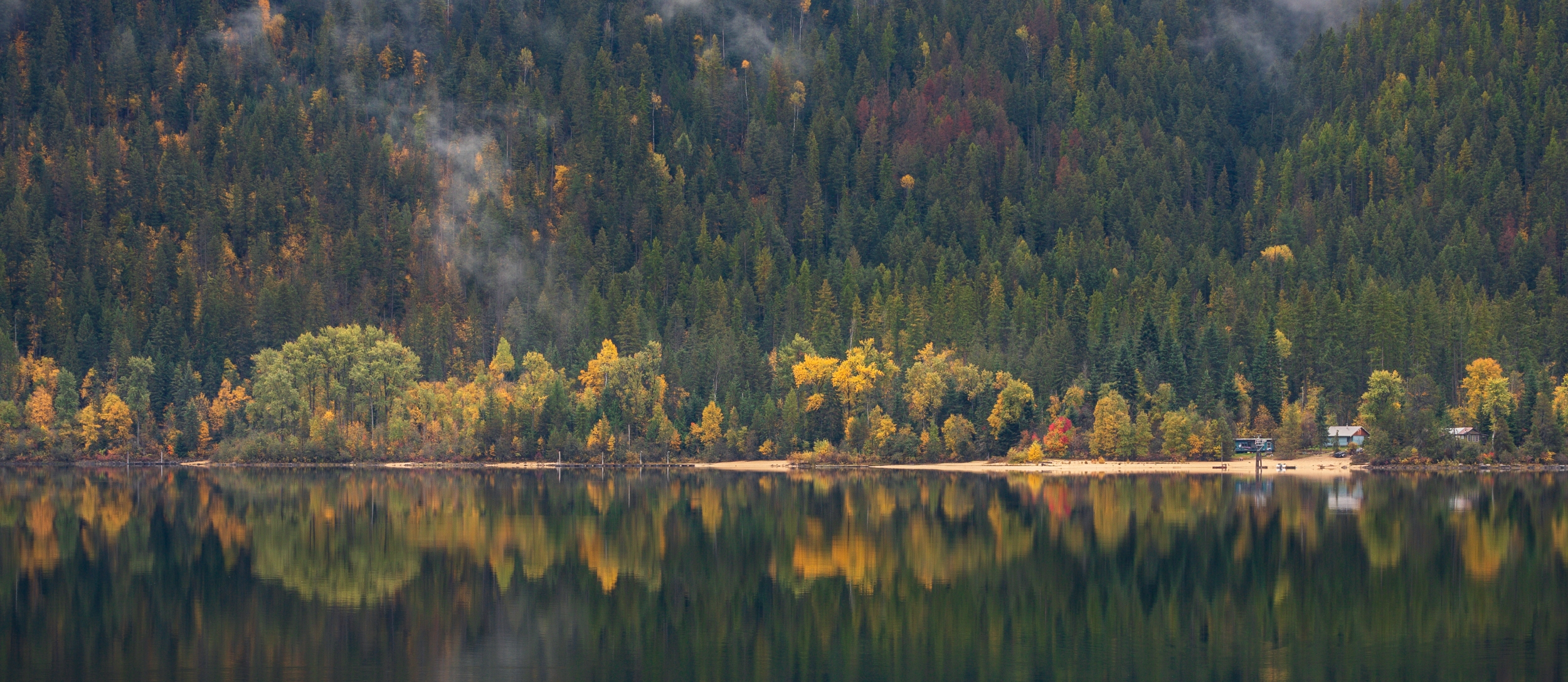 Fall colours reflecting on lake.