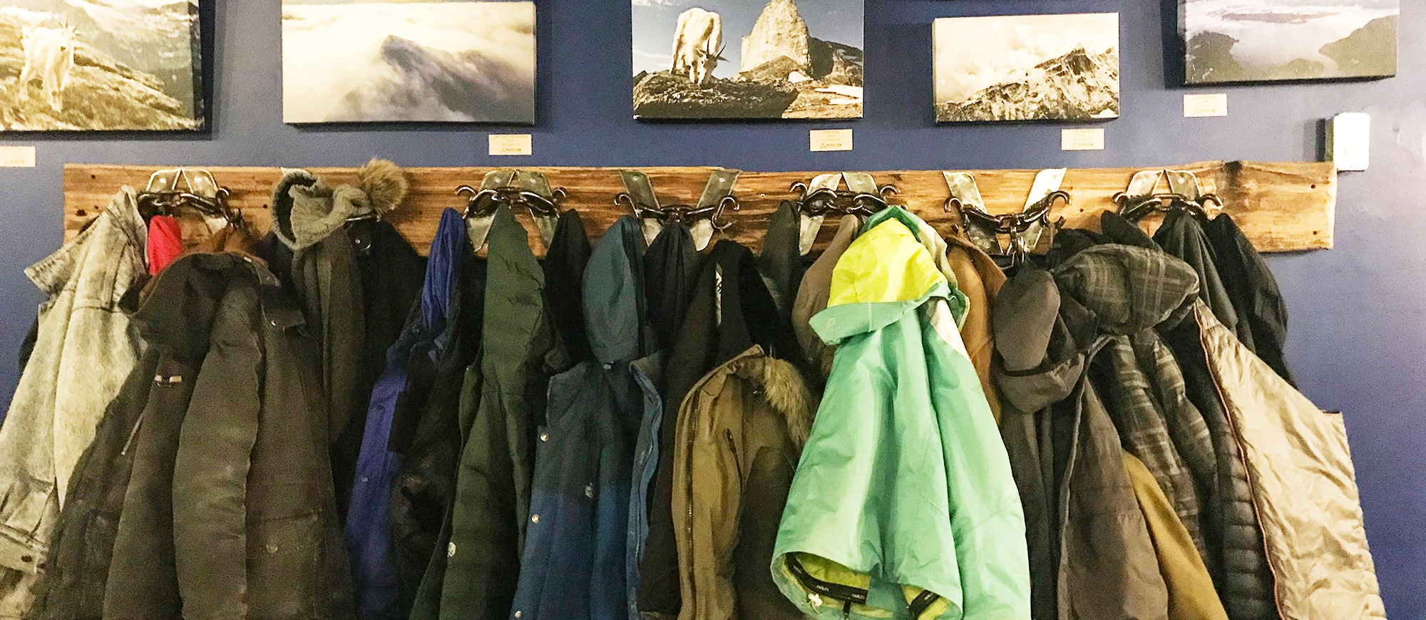 A rack of winter jackets below some canvas prints of snowy mountains in Nelson BC