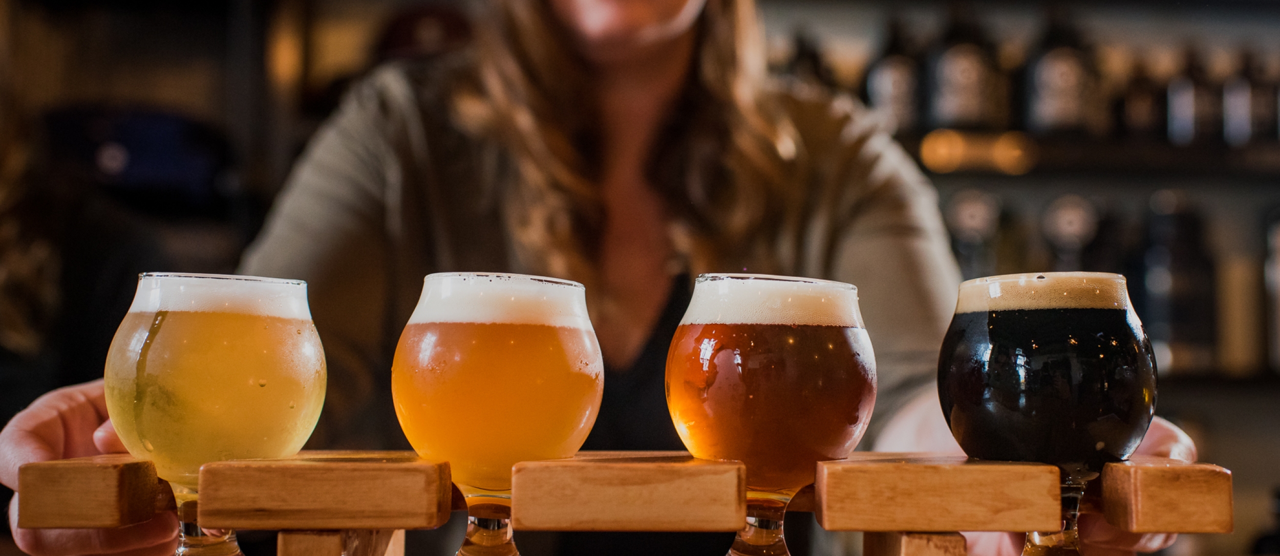 A bartender offers a flight of beer.