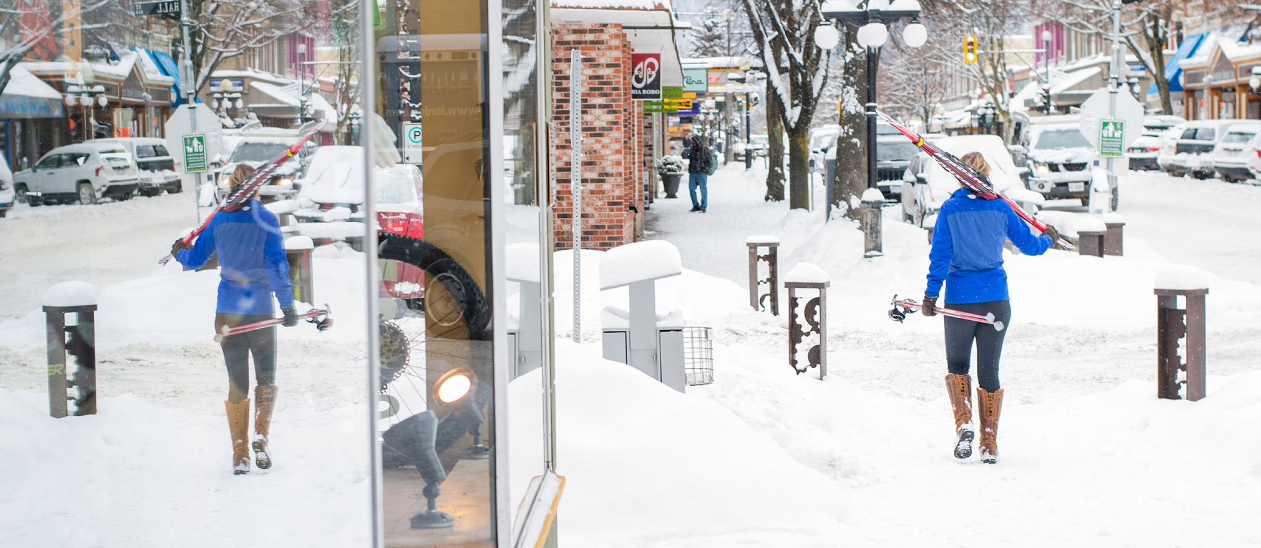 Woman walking downtown Nelson BC carrying cross country skis