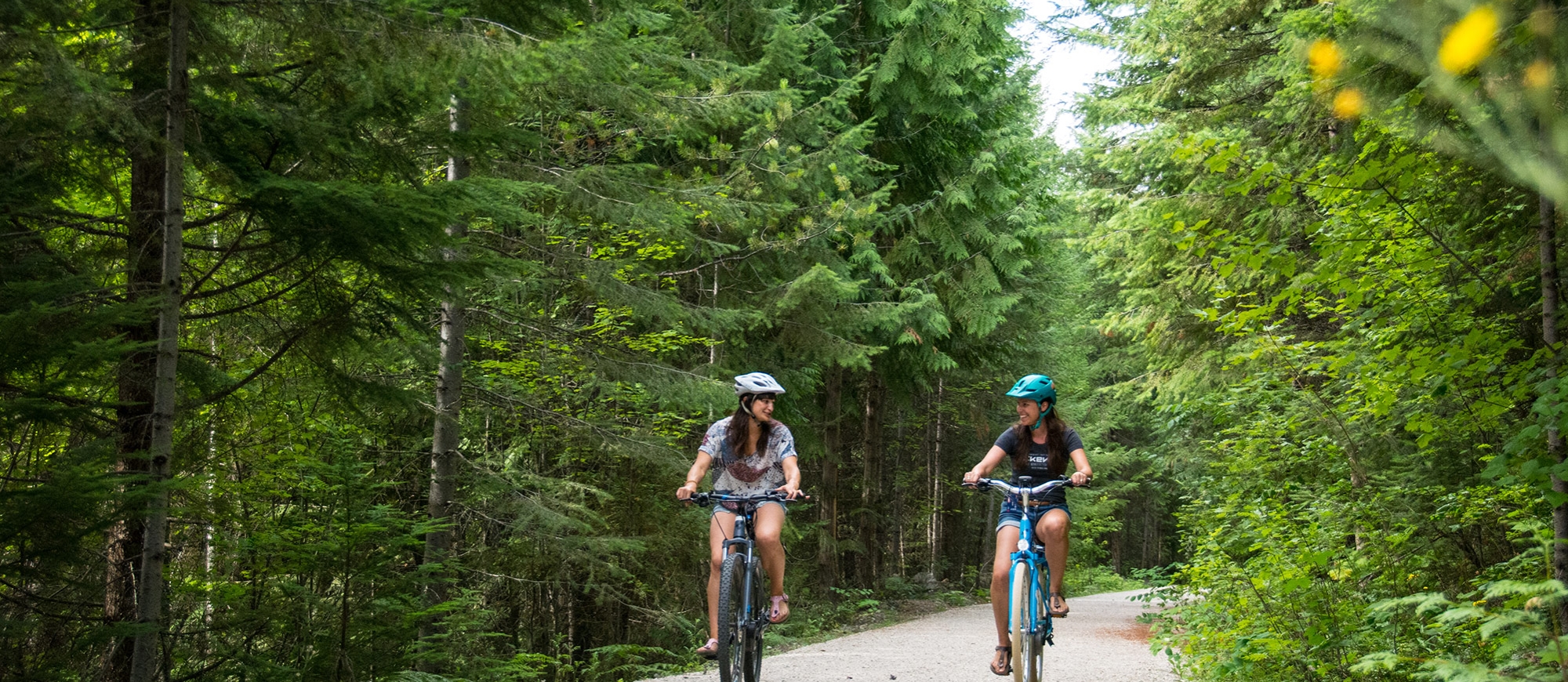 Two women cycling on the Great Northern Rail Trail above Nelson, BC on an ebikes