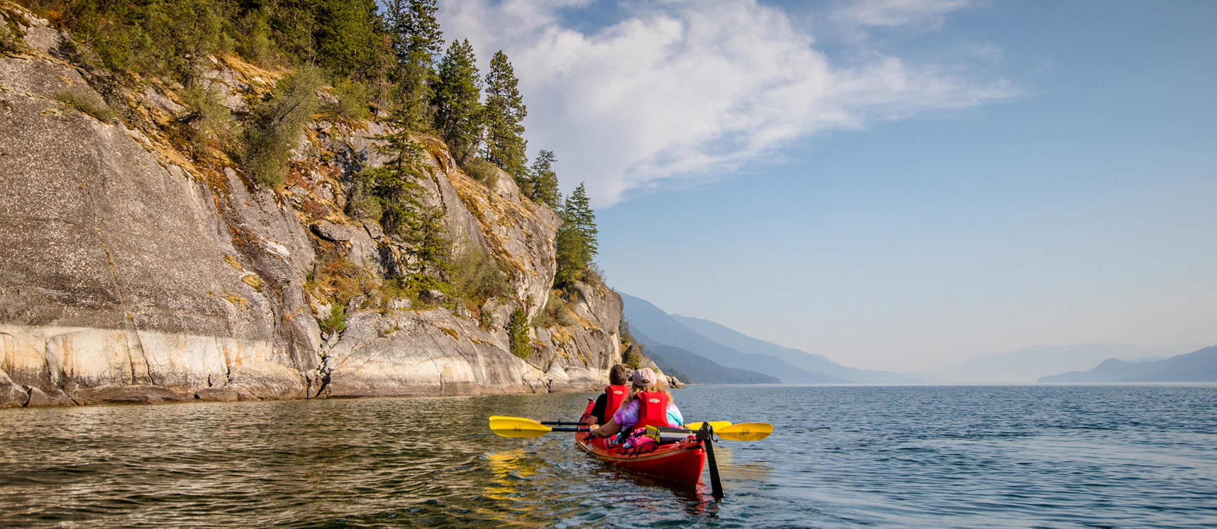 Two people on a double kayak paddling on Kootenay Lake near Kaslo, BC