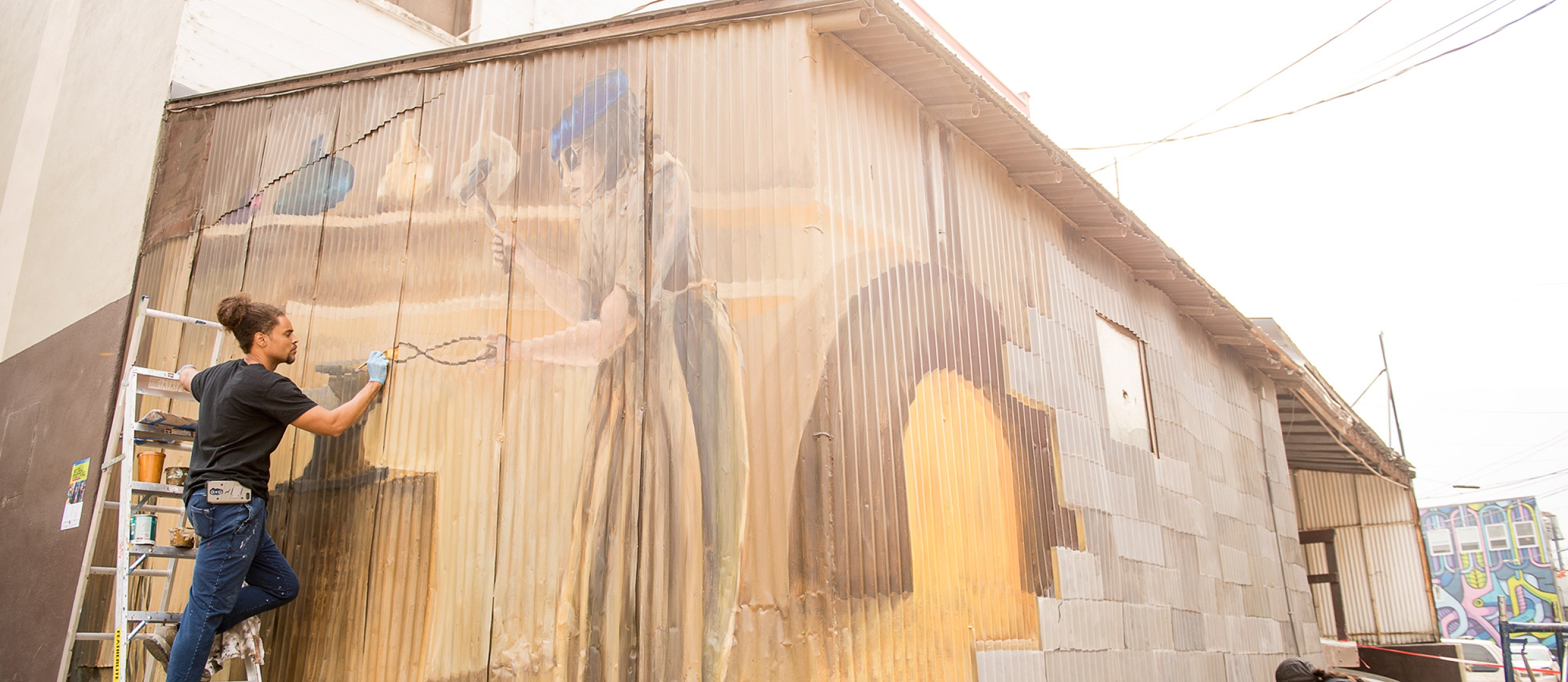 Two artists painting a mural during the Nelson International Mural Festival