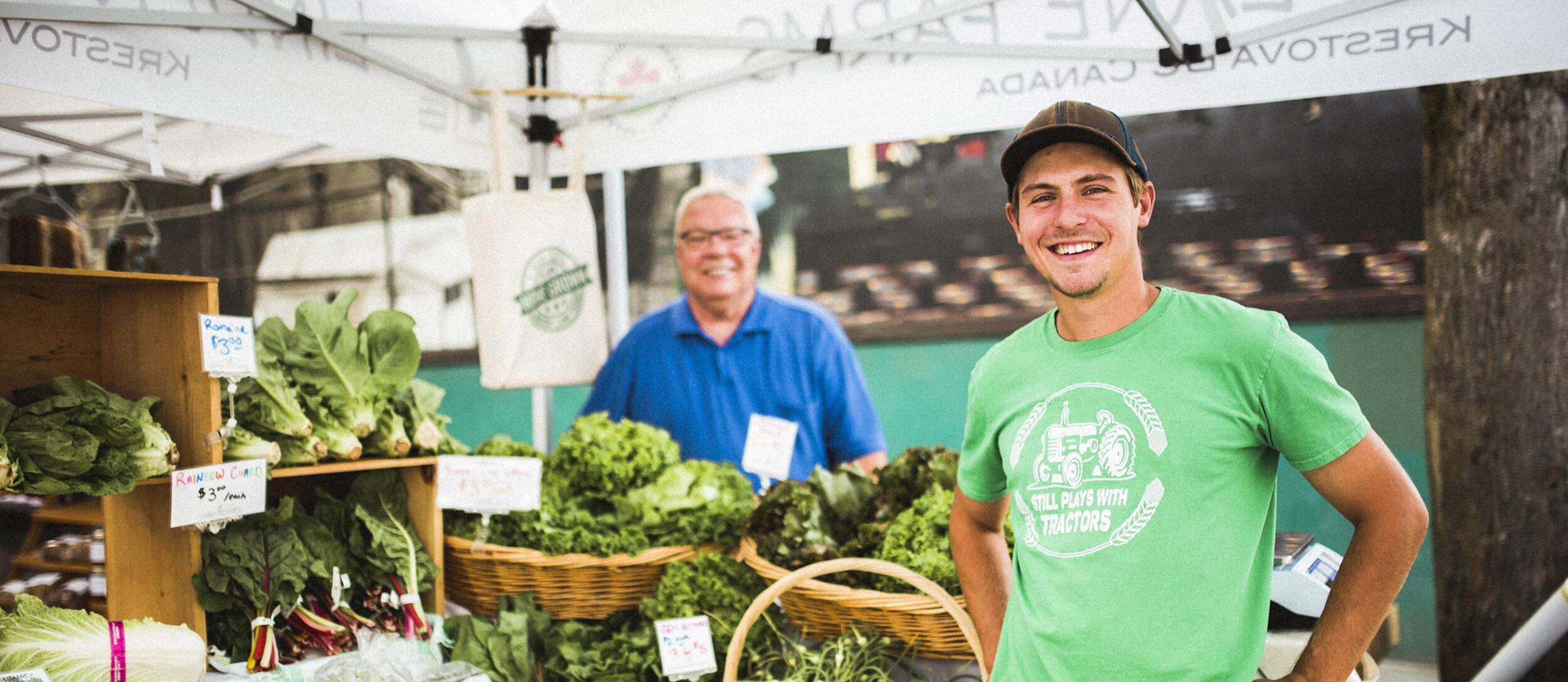 A farmer stands with a table full of produce at the Nelson Downtown Market