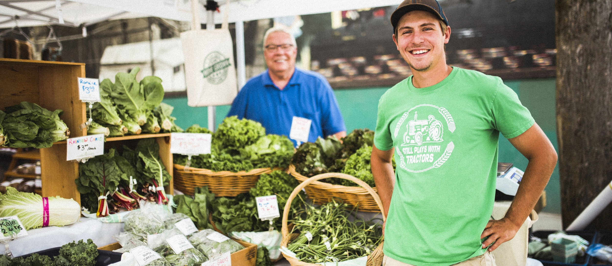 A farmer stands with a table full of produce at the Nelson Downtown Market