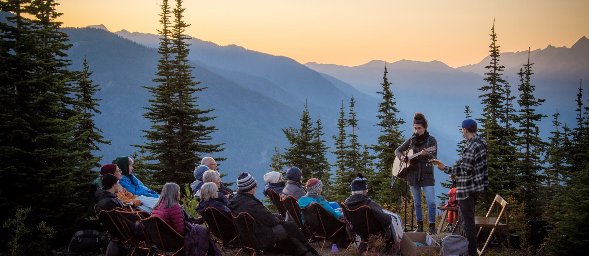 Artist Tenise Marie singing to a small crowd on the top of Mt Buchanan in Kaslo, BC at sunset.