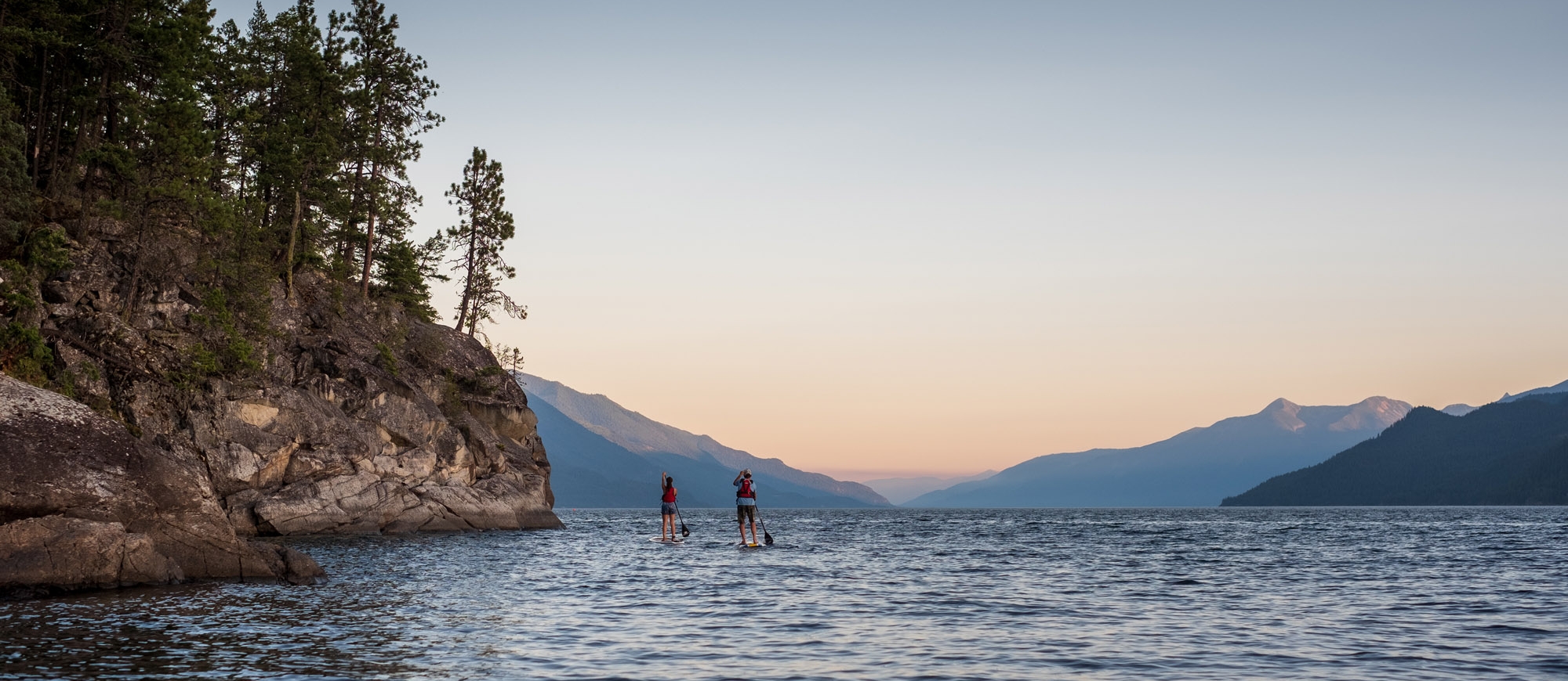 Two stand up paddle boarders on the East Shore of Kootenay Lake, BC.