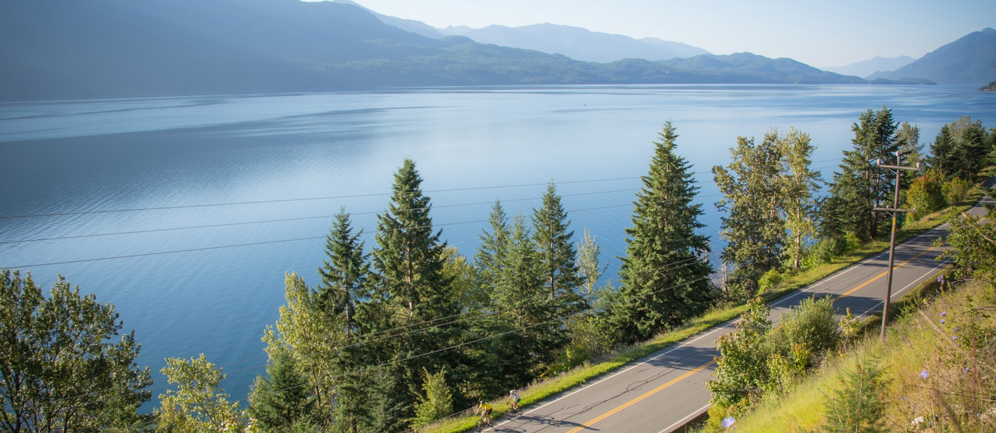 Two cyclists riding along the Highway near Kaslo, BC