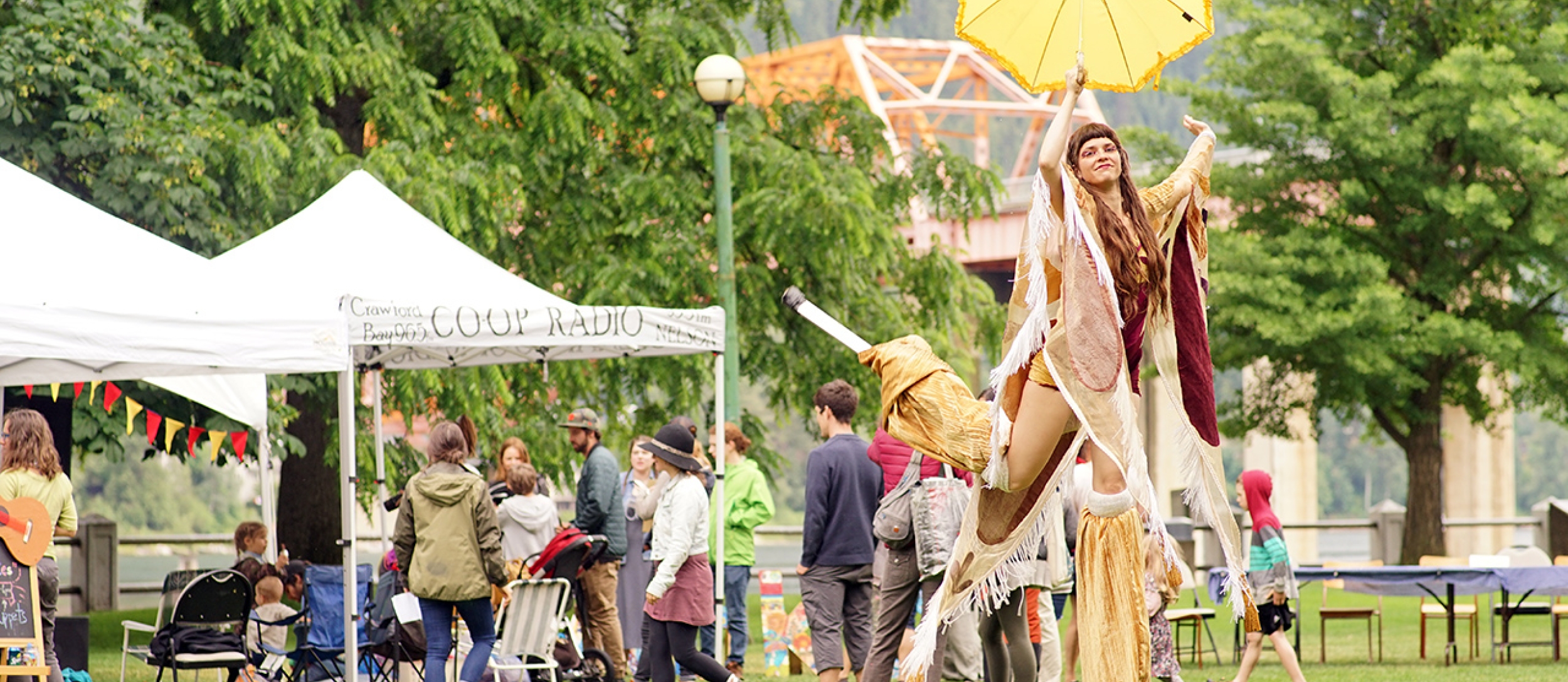 A lady walking on stilts in costume in the park for an AFKO gathering