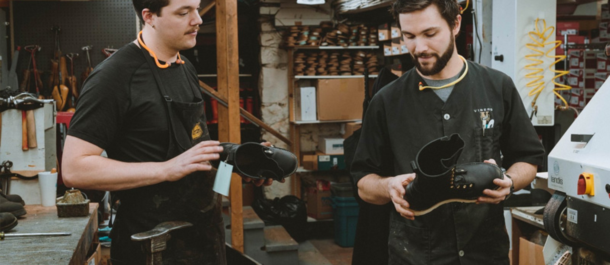 Seven of the staff at DeVito's shoes smiling, each holding a shoe,