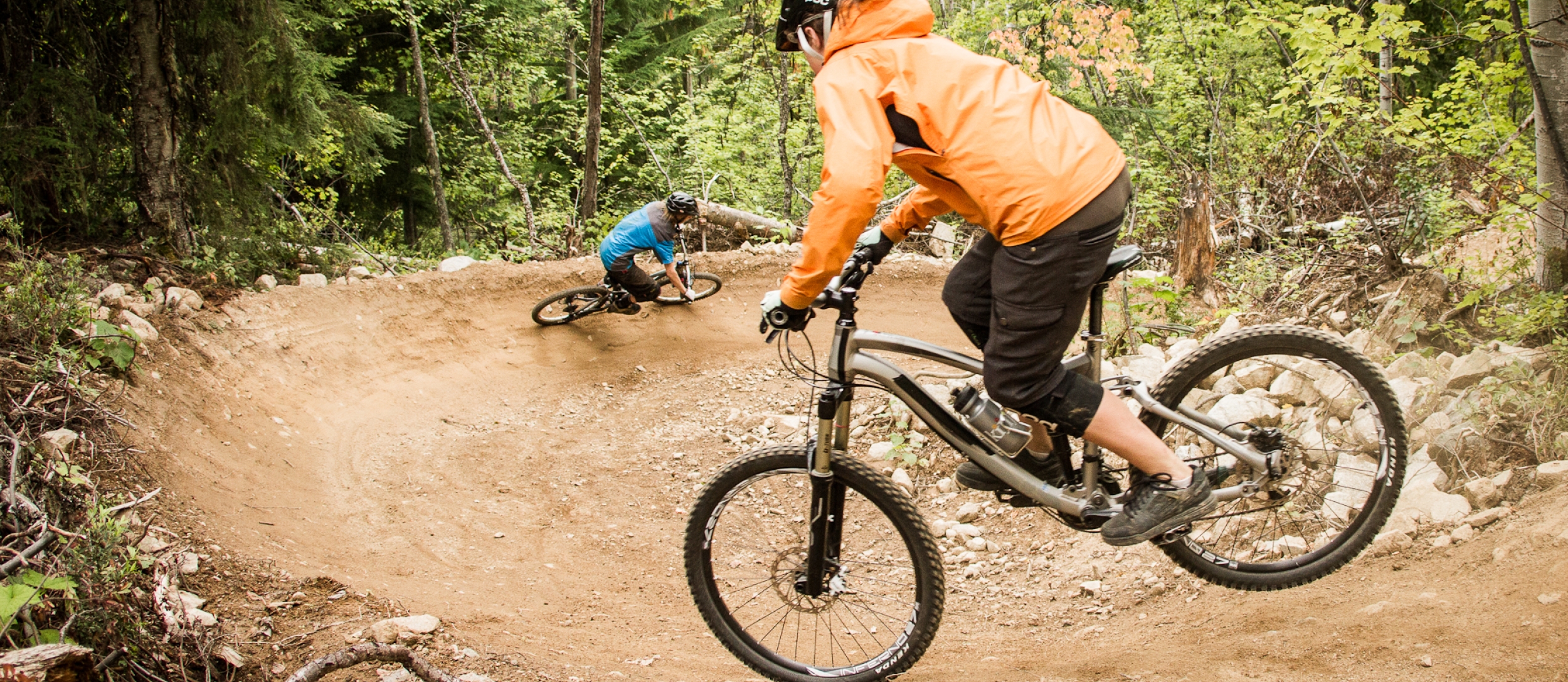 Two people riding down a machine built bike trail at Morning Mountain.