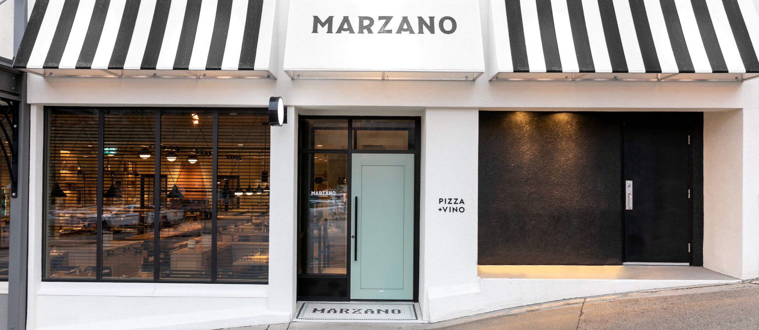 The outside of the Marzano restaurant showcasing white and black awnings