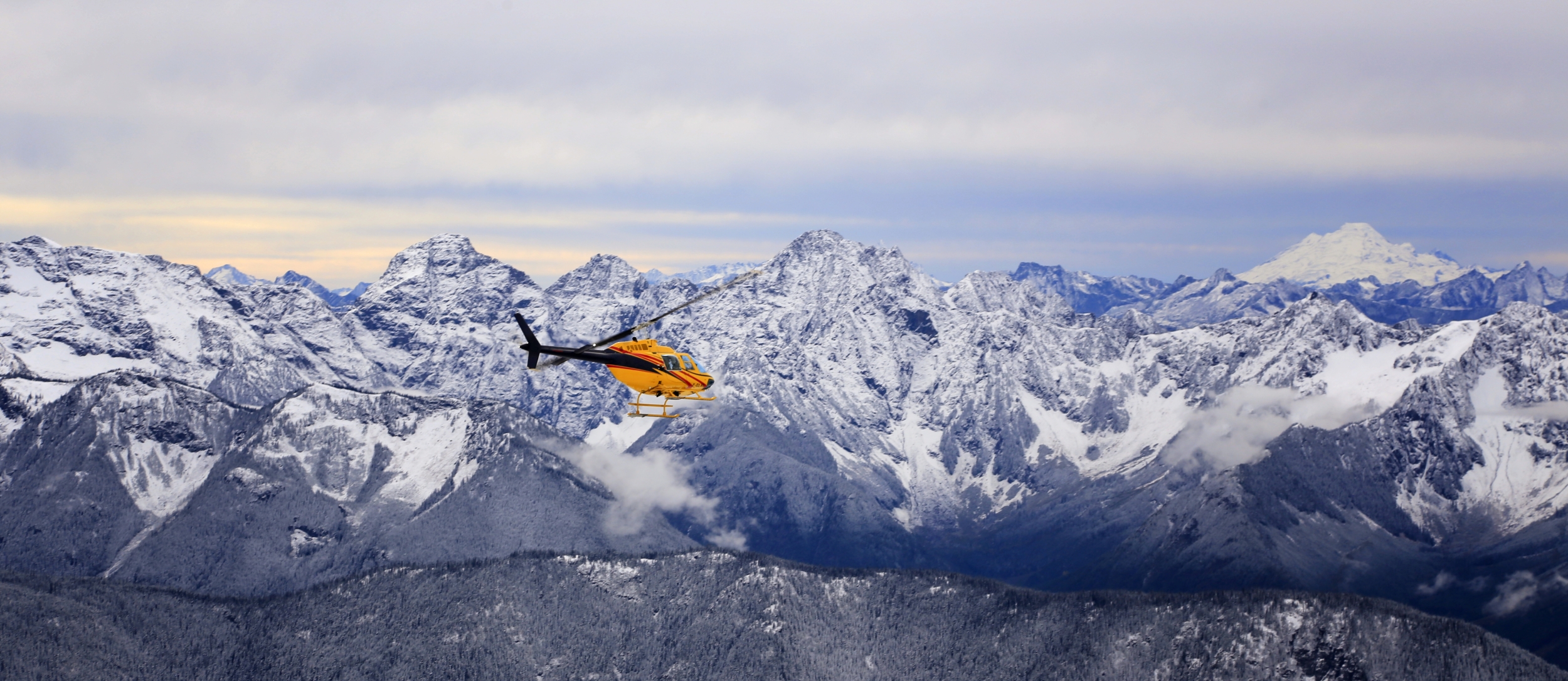 Helicopter flying over snow capped mountains