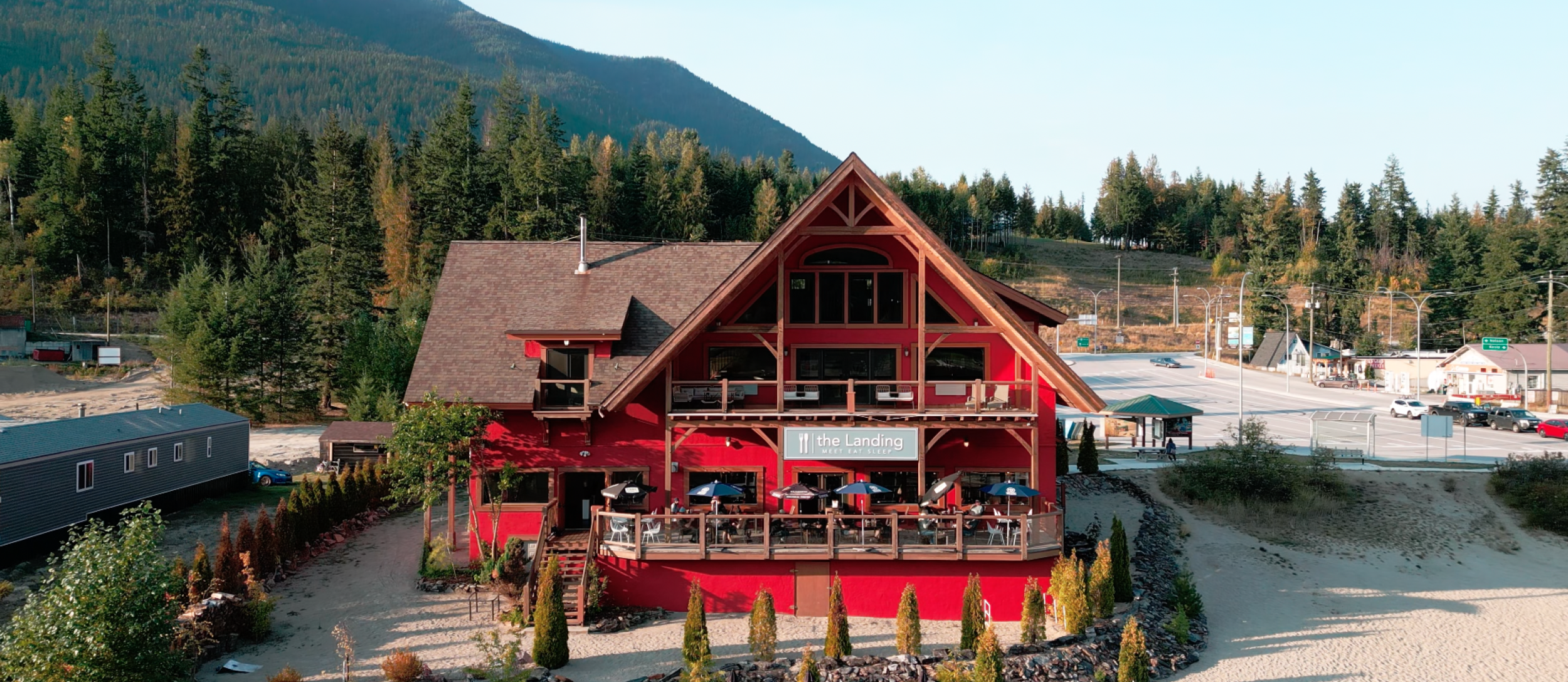The big, red building of The Landing with people dining on their patio.