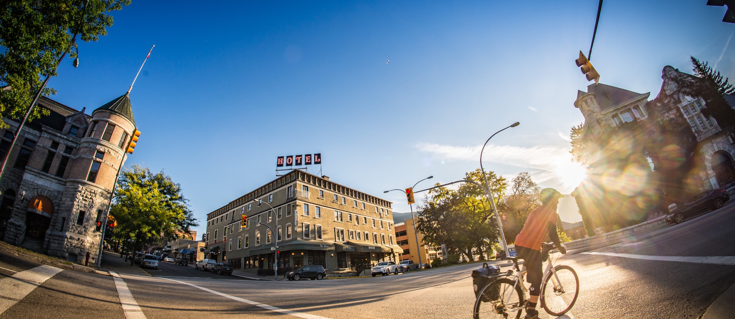 Man biking downtown Nelson with The Hume Hotel and the court house in the background