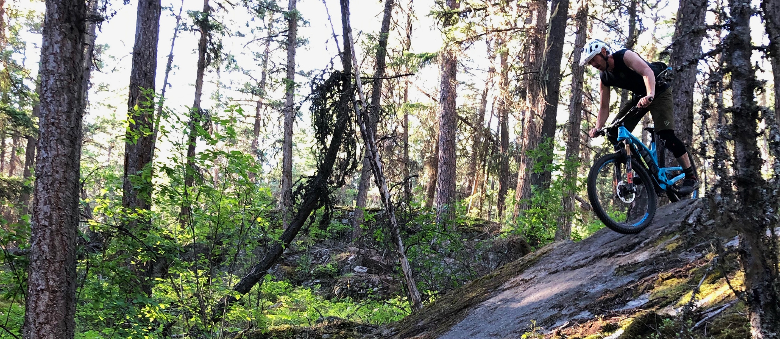 Person riding a mountain bike down a rock slab.