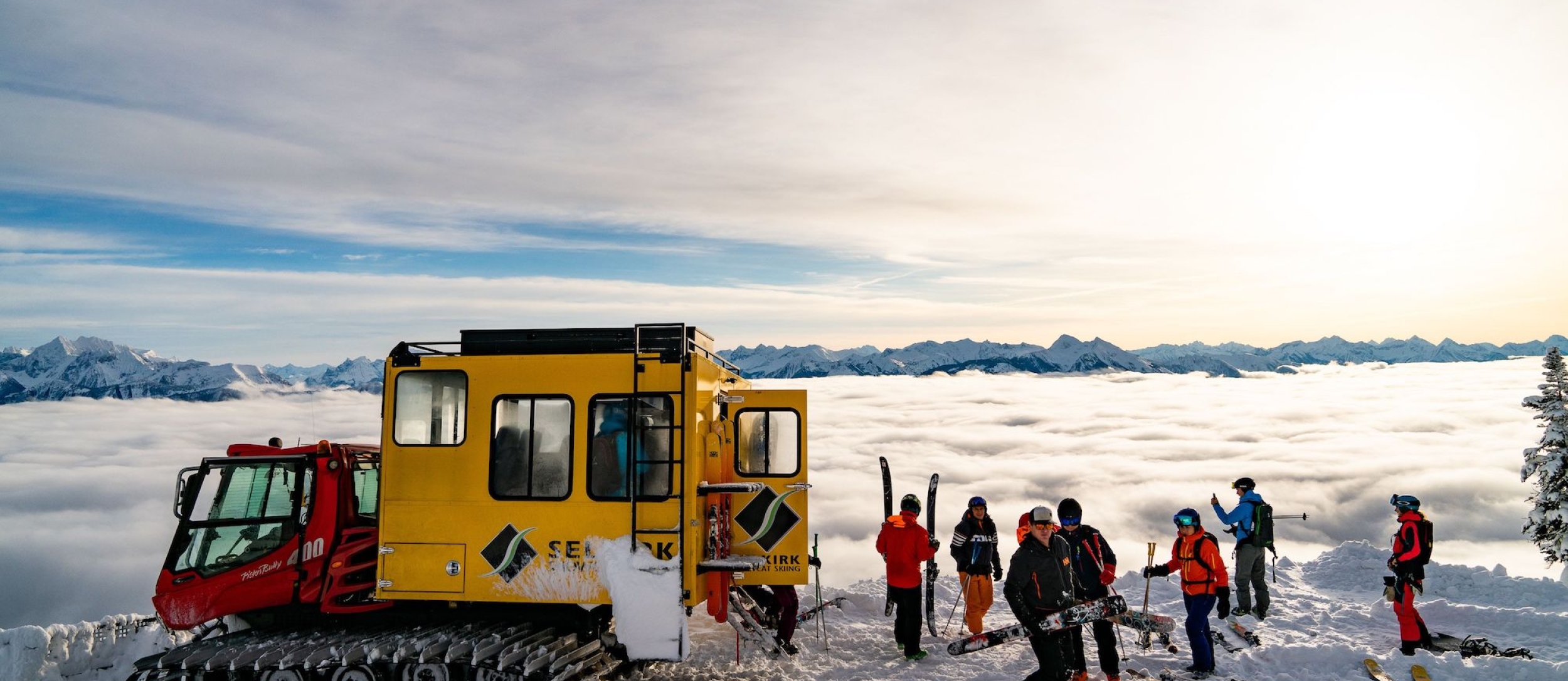 A Snowcat and skiiers in the snow at Selkirk Snowcat Skiing