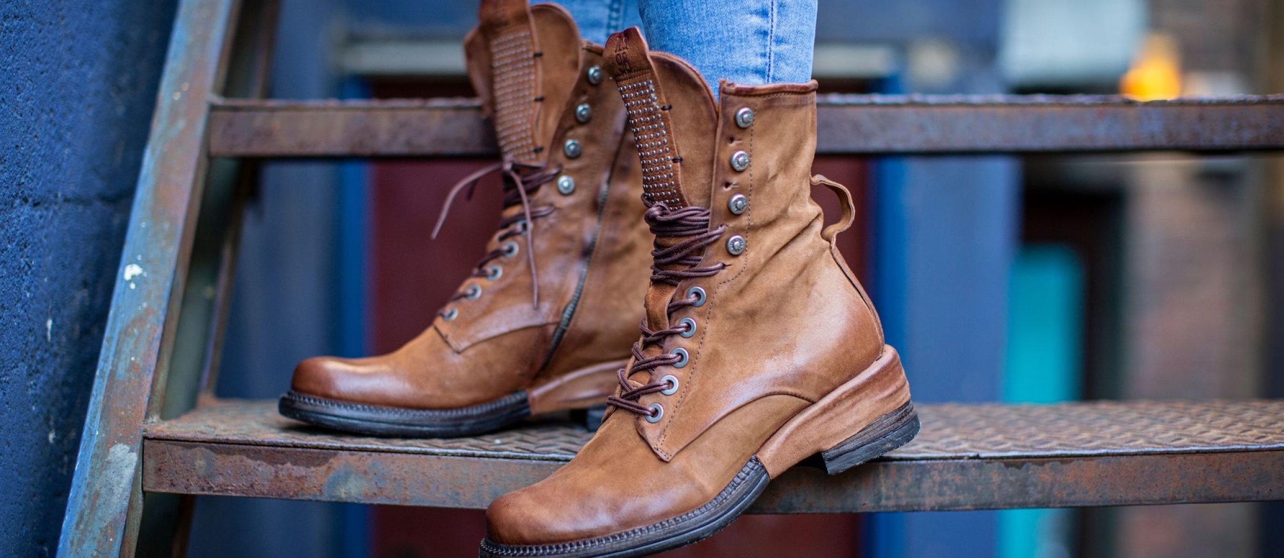 A woman stands on some stairs wearing brown high top boots from Shoes for the Soul