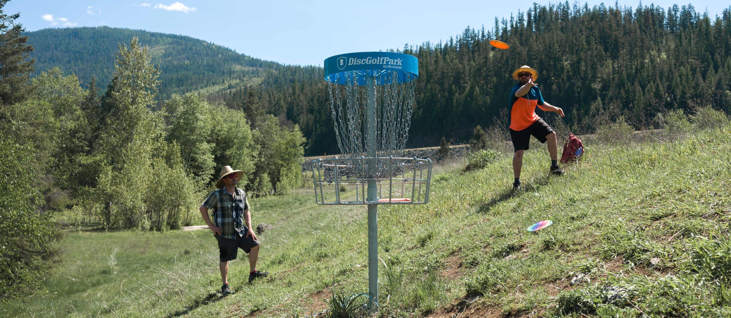 People playing disc golf with mountains in background.