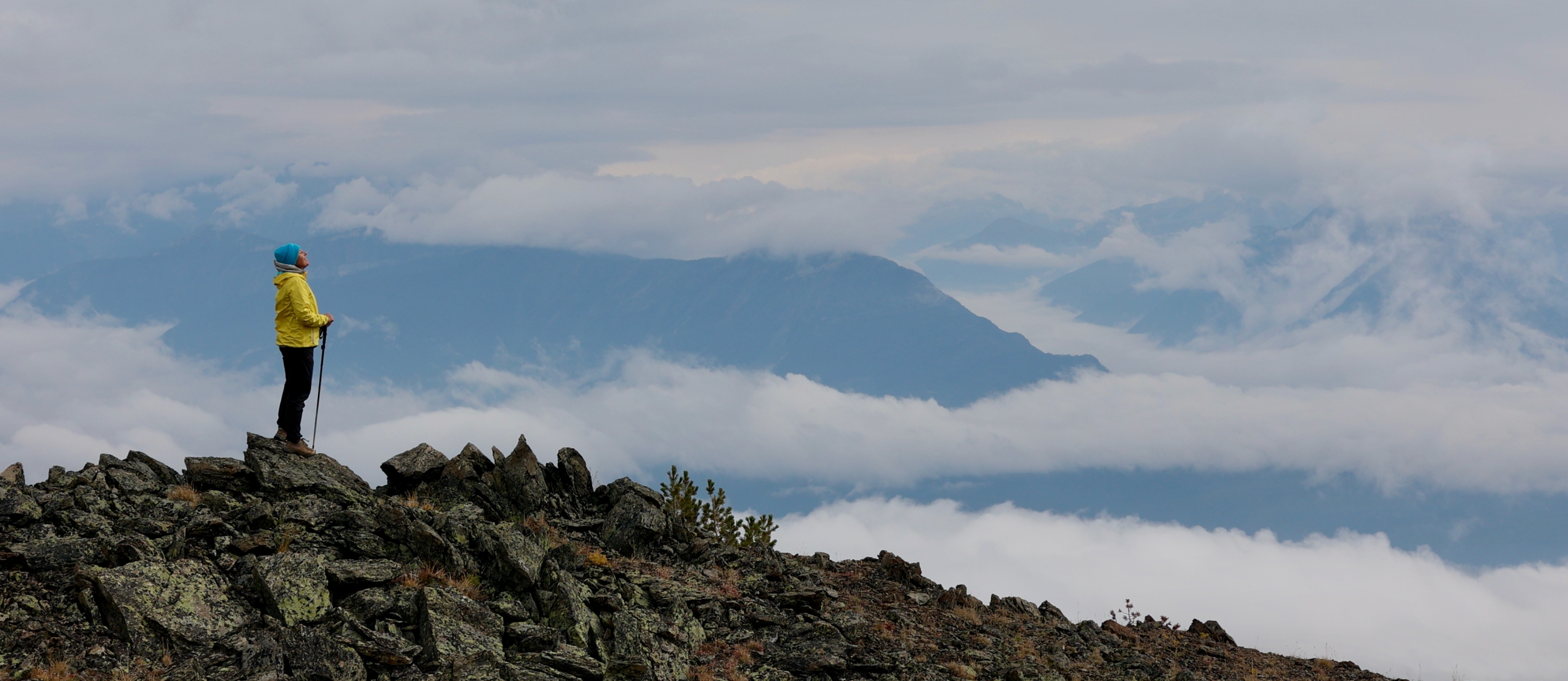 Woman standing on top of summit looking out into distance.