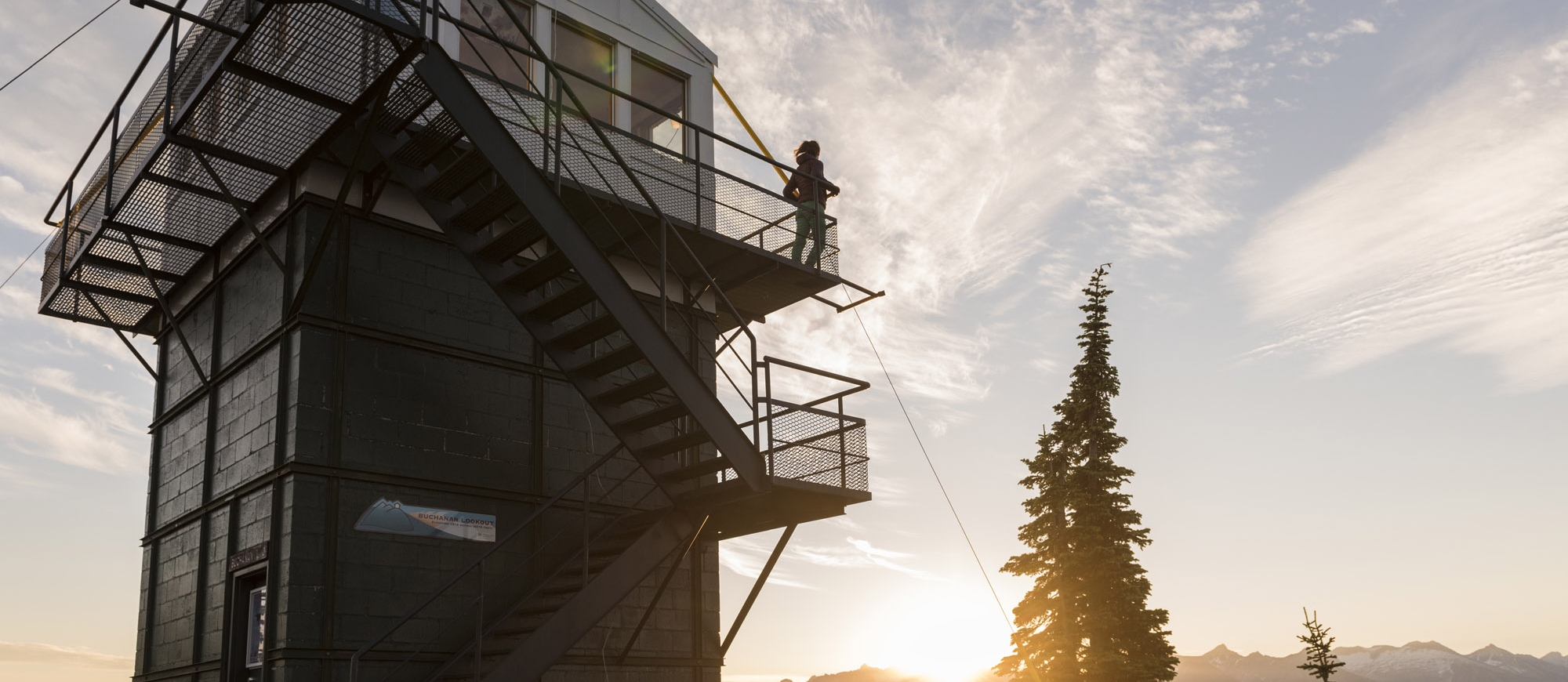 Someone standing on the balcony of the old fire watch tower on Mt Buchanan near Kaslo, BC