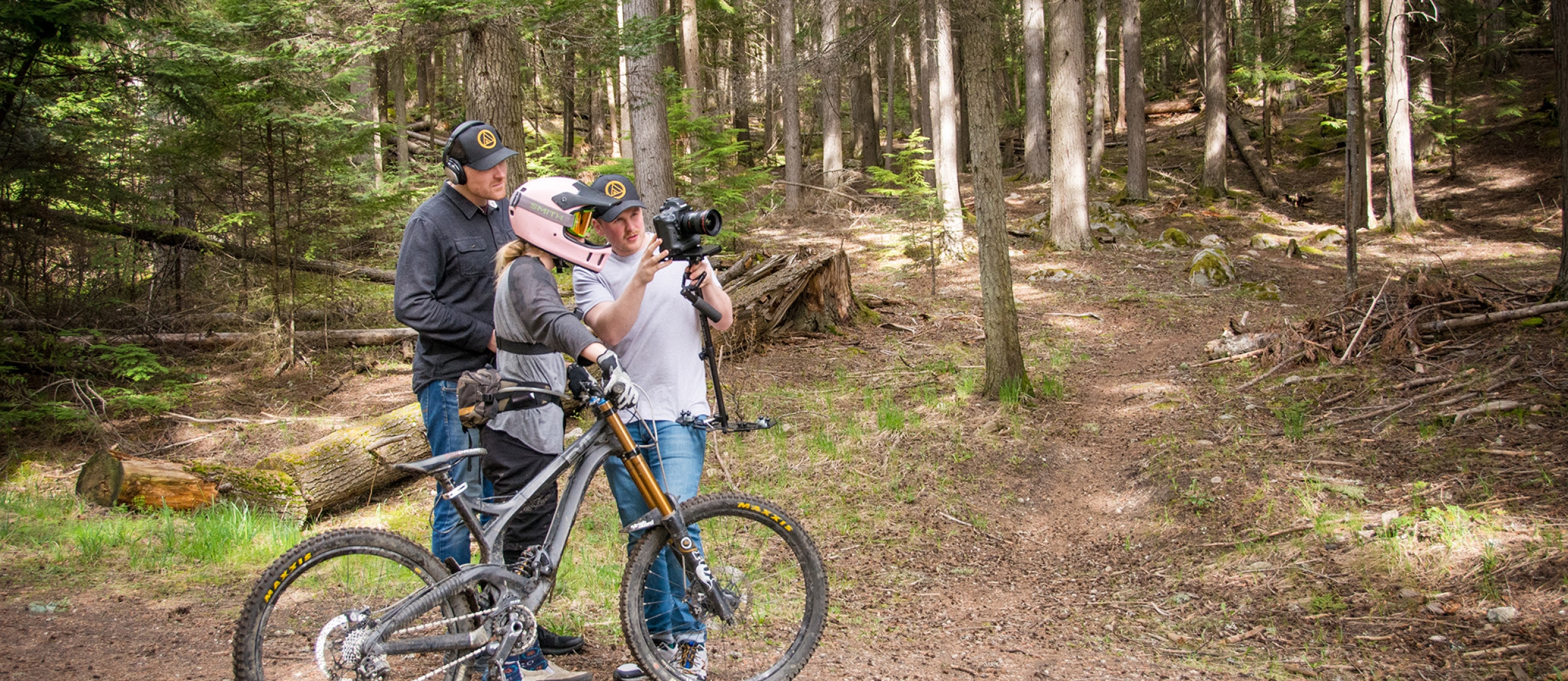 Two filmers reviewing footage off of a camera with a mountain biker