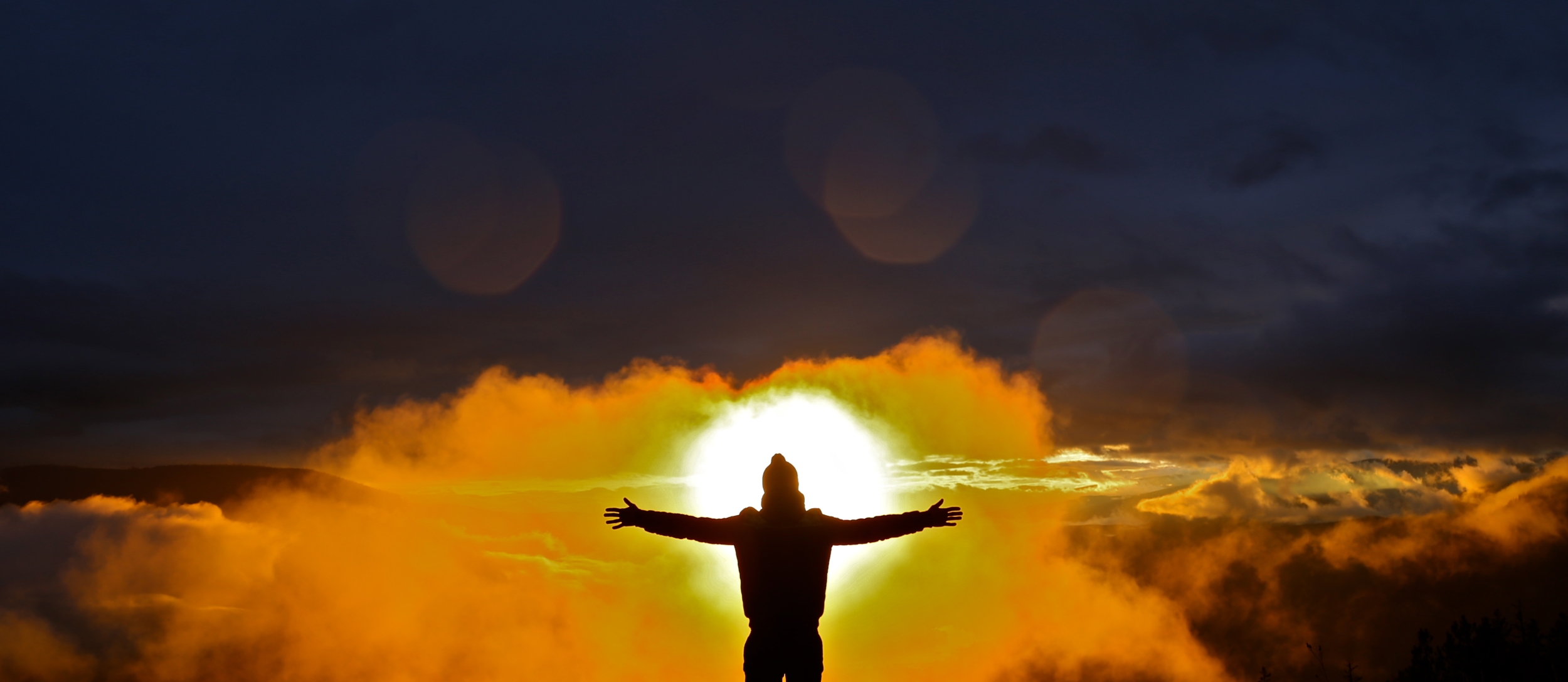 A man standing with his arms spread out on Pulpit Rock