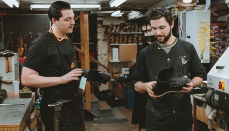 Seven of the staff at DeVito's shoes smiling, each holding a shoe,