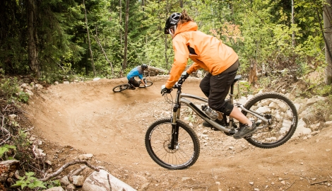 Two people riding down a machine built bike trail at Morning Mountain.