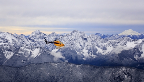 Helicopter flying over snow capped mountains