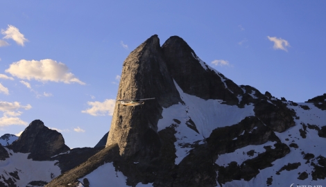 A Kootenay Lake Aviation plane flies near a large mountain