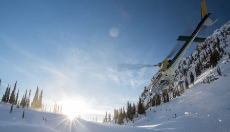 photo of a high terrain helicopter landing in the snow surrounded by mountains