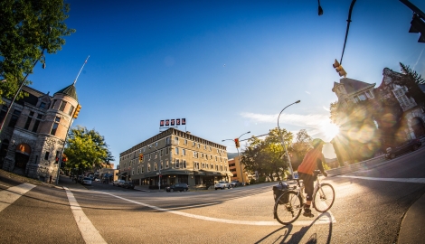 Man biking downtown Nelson with The Hume Hotel and the court house in the background