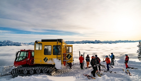 A Snowcat and skiiers in the snow at Selkirk Snowcat Skiing