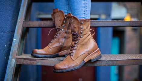 A woman stands on some stairs wearing brown high top boots from Shoes for the Soul