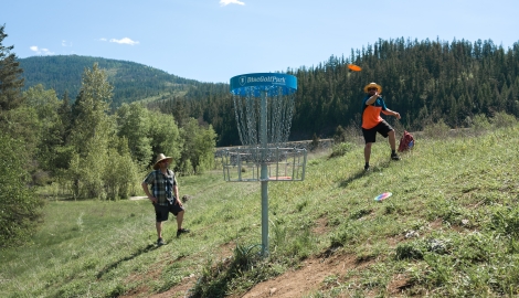 People playing disc golf with mountains in background.